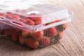 red ripe strawberry in plastic box of packaging on wood table